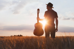 Man holding a guitar in a beautiful field