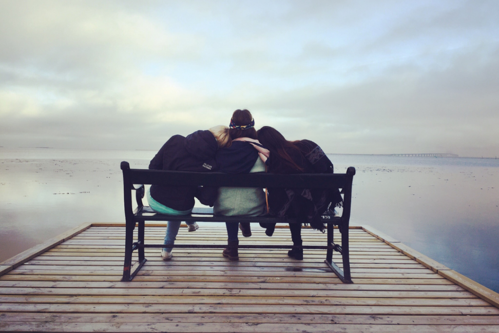Three people sitting on a bench together