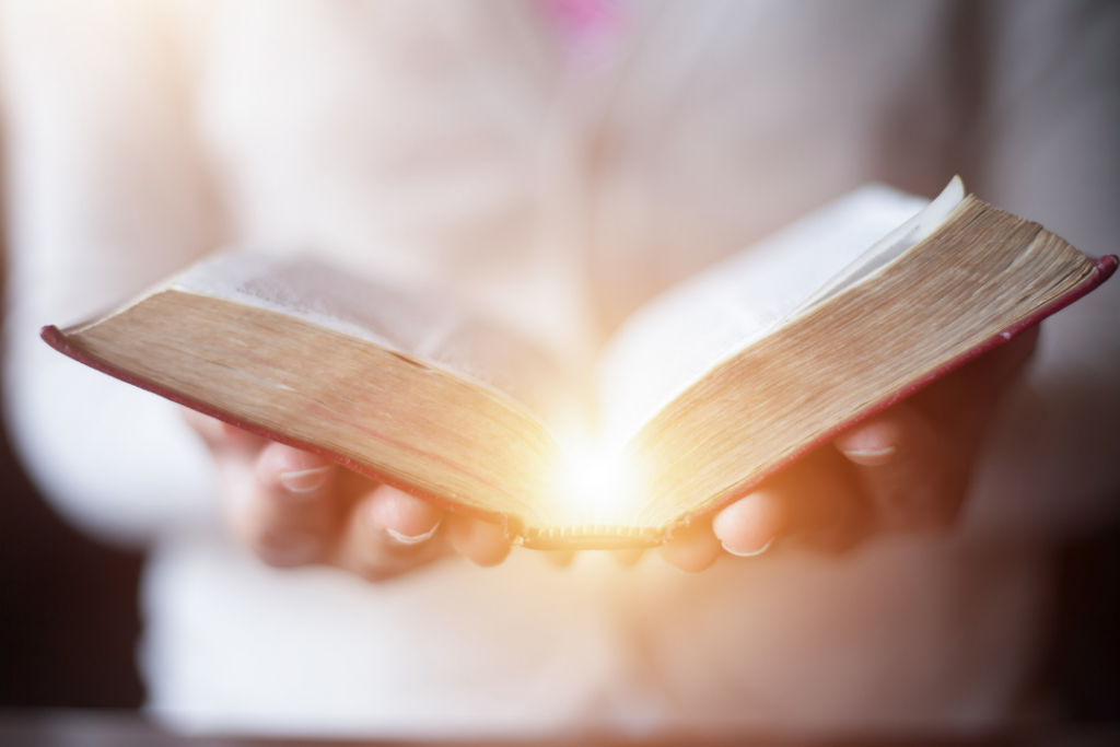 A woman holding a Bible open with a glow coming from the pages